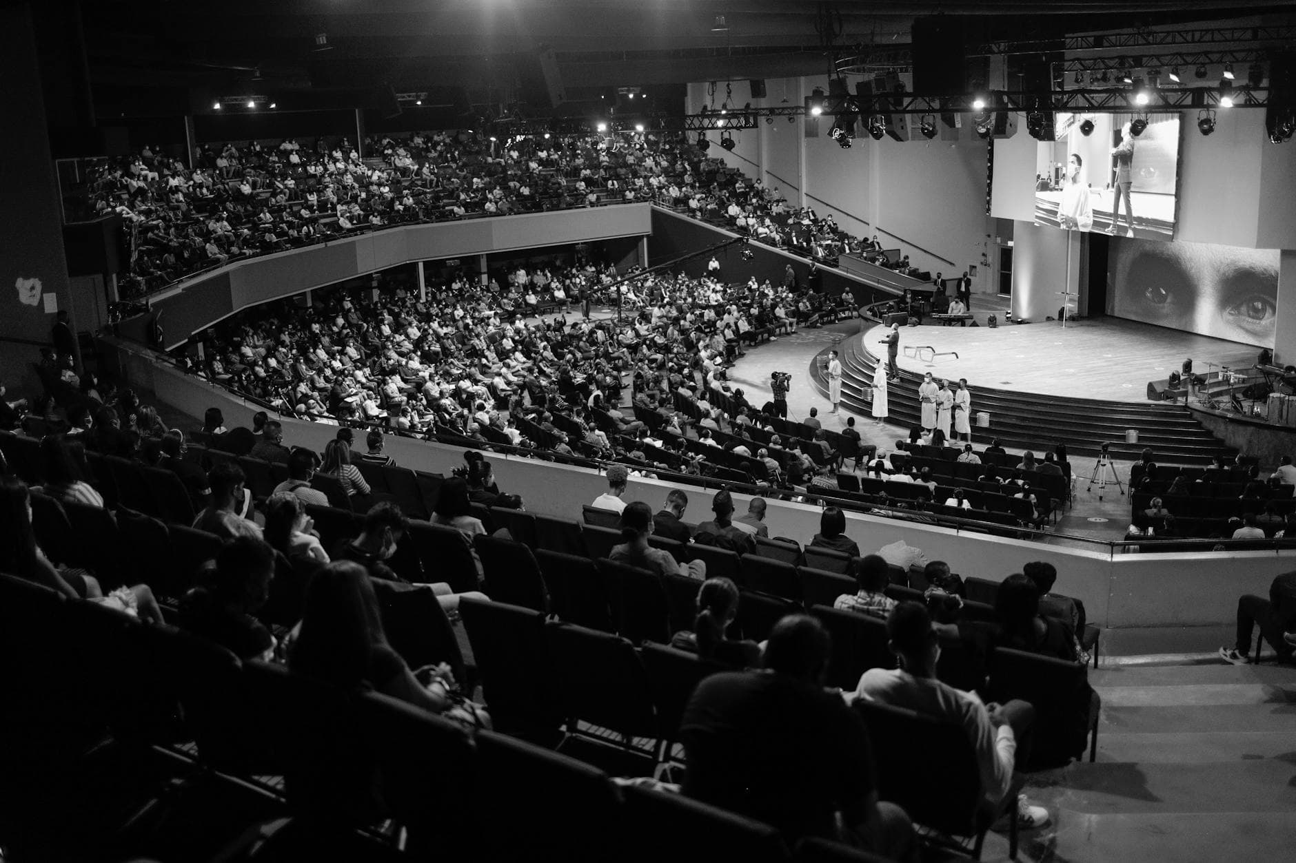 Packed ballroom with stage lighting, black and white
